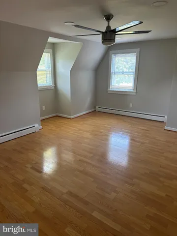 an empty room with wooden floor cabinet and windows