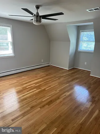 an empty room with wooden floor fan and windows