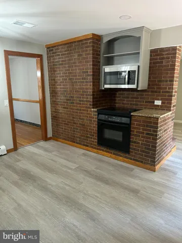 a view of an empty room with wooden floor and a fireplace