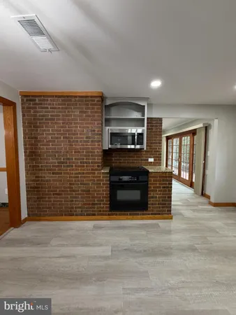 a view of kitchen with stainless steel appliances wooden floor and large window