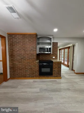 a view of kitchen with stainless steel appliances wooden floor and large window