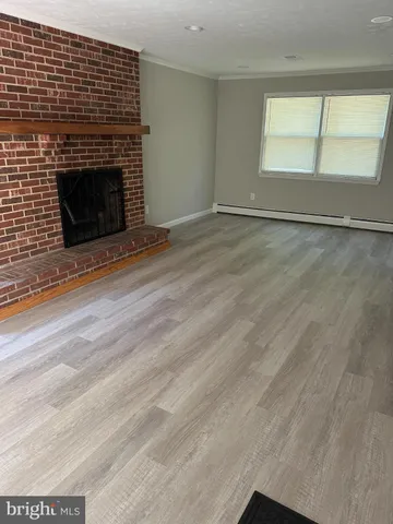 an empty room with wooden floor fireplace and windows
