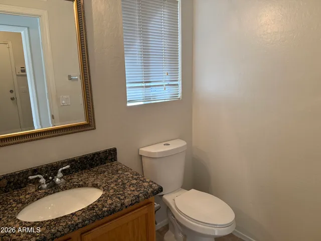 a bathroom with a granite countertop sink toilet a mirror and a window