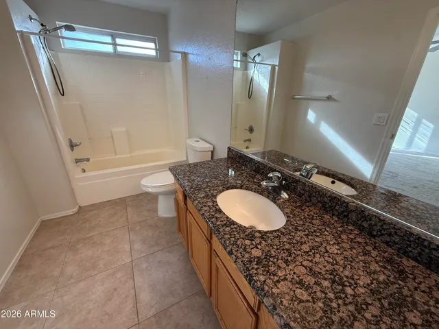 a bathroom with a granite countertop double vanity sink a mirror and a bathtub
