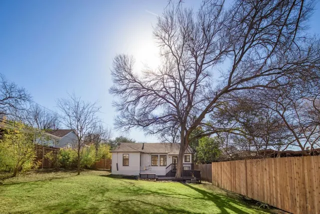 a view of a yard in front of a house with large trees