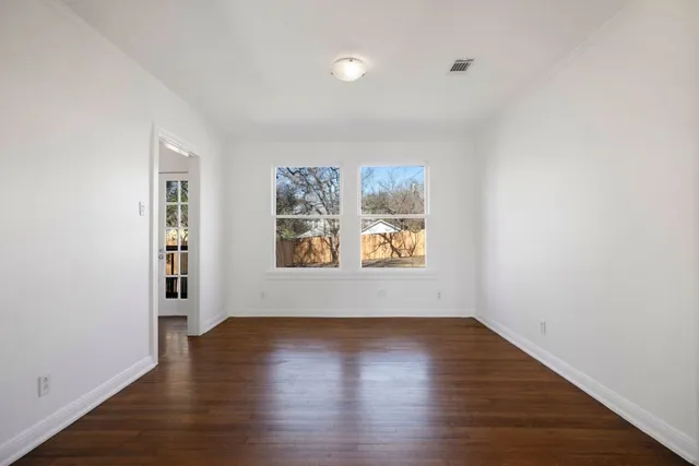 an empty room with window and wooden floor