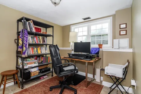 a view of a workspace with bookshelf and a window