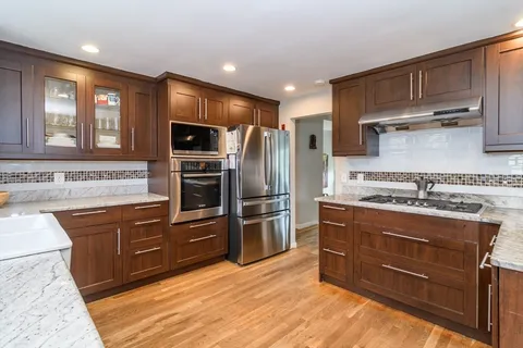 a kitchen with stainless steel appliances granite countertop a stove refrigerator and cabinets