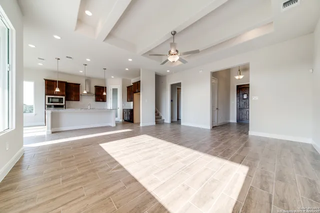 an empty room with wooden floor and a kitchen