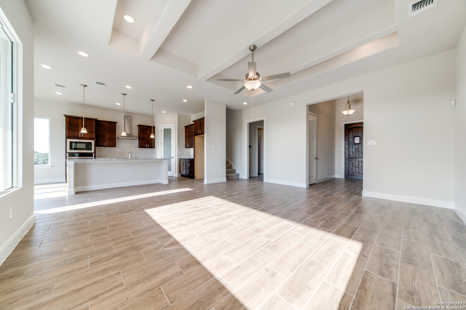238 Peter Kleid Loop Blanco, TX 78606 - Photo 11 of 25 an empty room with wooden floor and a kitchen
