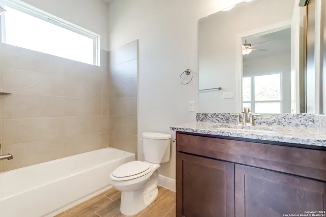 a bathroom with a granite countertop toilet a sink and a bathtub
