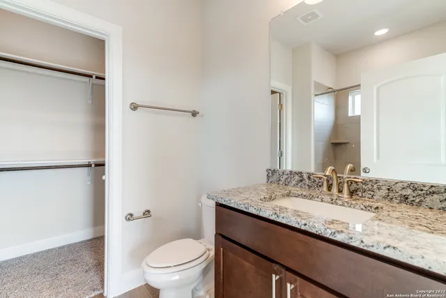 a bathroom with a granite countertop sink toilet and shower