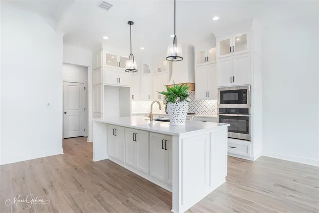 a kitchen with stainless steel appliances kitchen island wooden floors cabinets and entryway