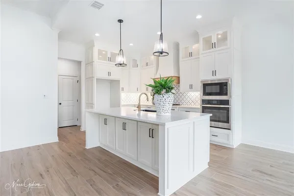 a kitchen with stainless steel appliances kitchen island wooden floors cabinets and entryway