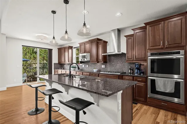 a kitchen with stainless steel appliances granite countertop a stove a sink a microwave a refrigerator a stove a kitchen island with a cabinets and floor