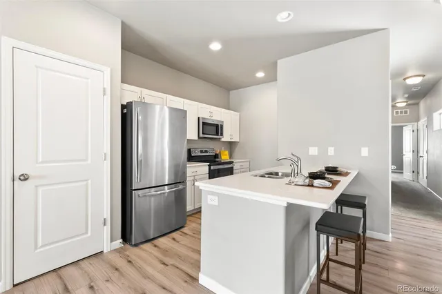 a kitchen with a refrigerator a stove a sink and a dining table with wooden floor