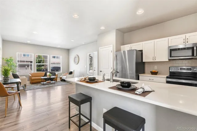 a kitchen with a sink a stove and chairs with wooden floor