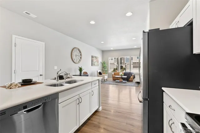 a kitchen with a sink dishwasher a refrigerator and a stove with wooden floor