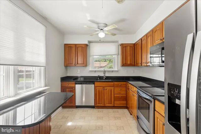 a kitchen with stainless steel appliances granite countertop a sink a stove a refrigerator cabinets and a dining table