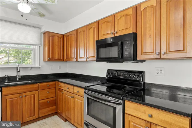 a kitchen with granite countertop cabinets stainless steel appliances a sink and a window