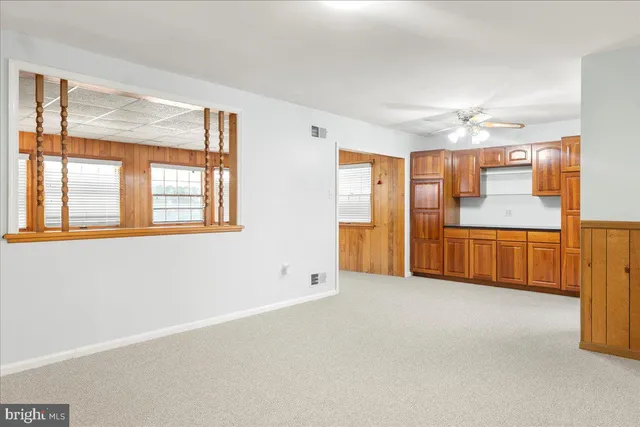 a view of an empty room with window and kitchen view