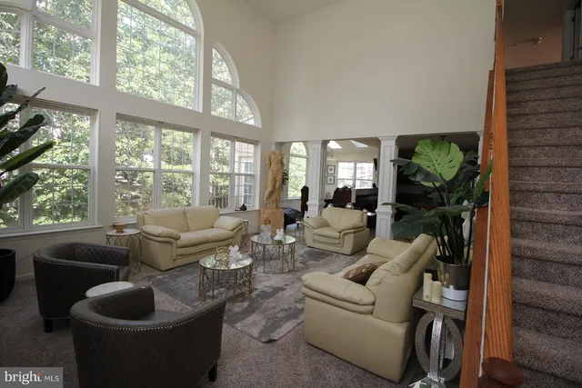 a living room with furniture potted plant floor to ceiling windows and a flat screen tv