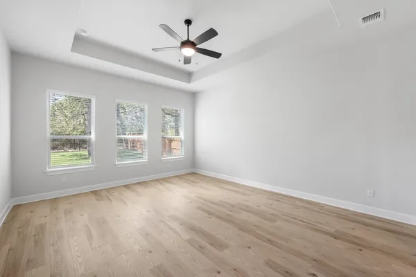 a view of an empty room with wooden floor fireplace and a window