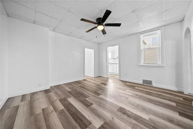 a view of empty room with wooden floor and ceiling fan