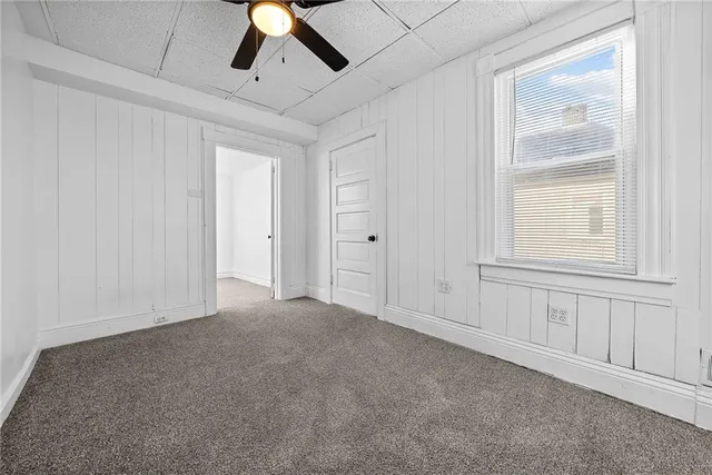an empty room with chandelier fan and windows