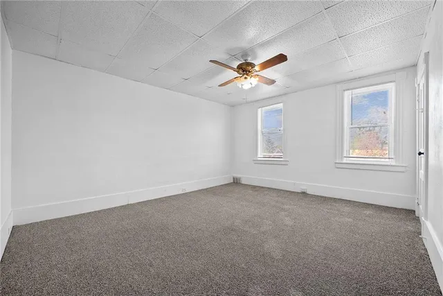 an empty room with windows and fan