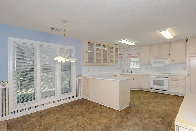 a kitchen with white cabinets and window