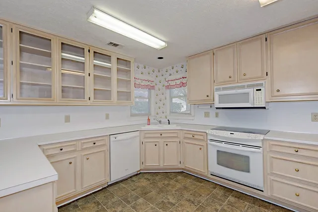 a kitchen with white cabinets and white appliances