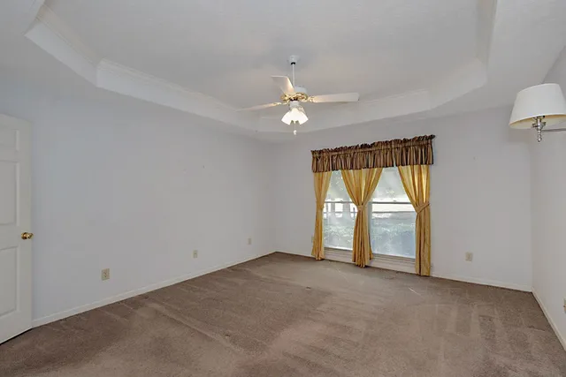 an empty room with windows and ceiling fan