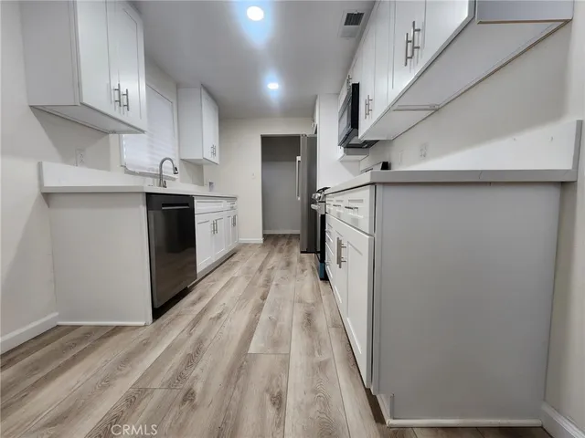 a kitchen with white cabinets and stainless steel appliances