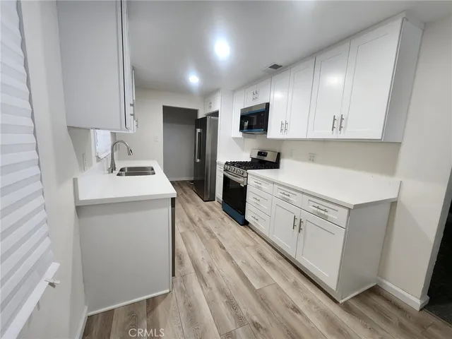 a kitchen with white cabinets appliances and sink