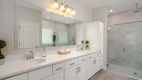 a bathroom with a double vanity sink mirror and shower