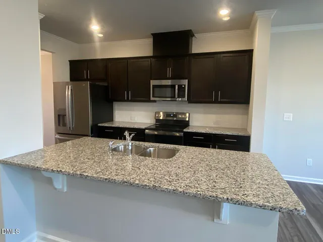 a kitchen with kitchen island granite countertop a refrigerator and a sink