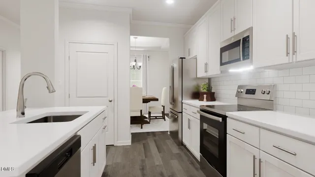a kitchen with a sink dishwasher a stove and white cabinets with wooden floor