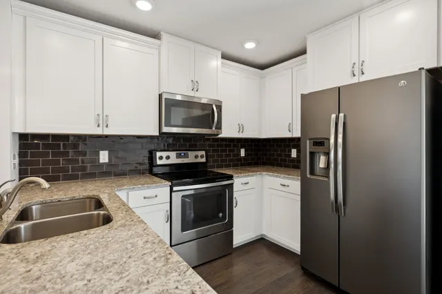 a kitchen with stainless steel appliances granite countertop a refrigerator a stove a sink and a microwave