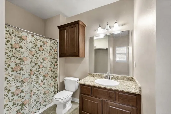 a bathroom with a granite countertop sink a toilet and a mirror