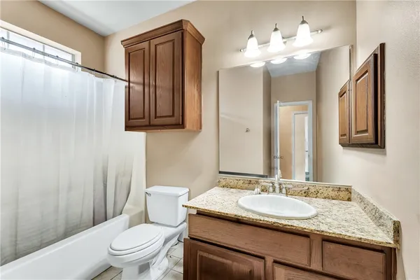 a bathroom with a granite countertop sink toilet and mirror