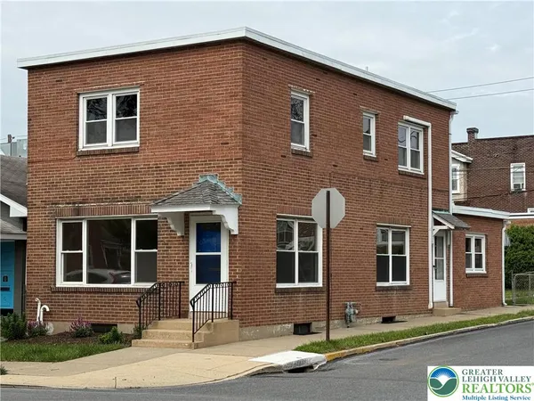 a front view of a house with yard and parking space