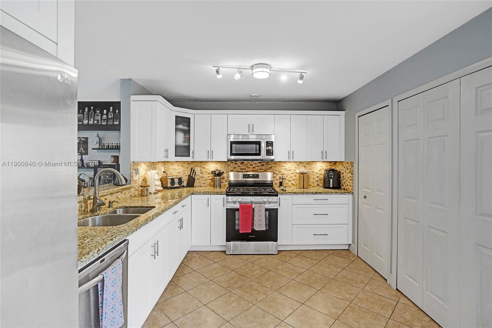 12221 Southwest 144th Terrace Miami, FL 33186 - Photo 11 of 42 a kitchen with stainless steel appliances granite countertop a sink and cabinets