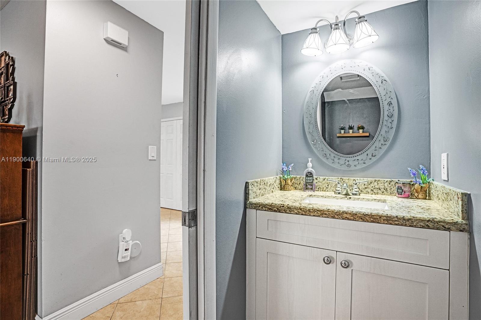 12221 Southwest 144th Terrace Miami, FL 33186 - Photo 6 of 42 a bathroom with a granite countertop sink mirror and vanity