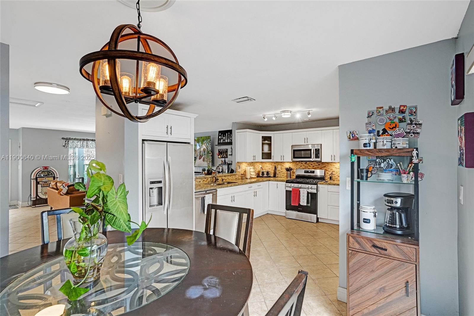 12221 Southwest 144th Terrace Miami, FL 33186 - Photo 10 of 42 a dining room with furniture a kitchen view and a chandelier