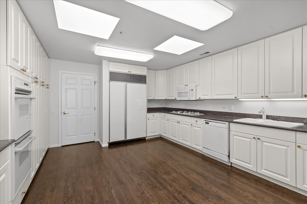 380 Green Bay Road, Unit 4D Winnetka, IL 60093 - Photo 14 of 25 a kitchen with granite countertop white cabinets and wooden floor
