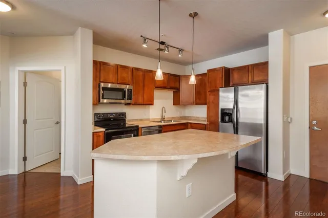 a kitchen with stainless steel appliances a refrigerator a stove a sink and a wooden floor