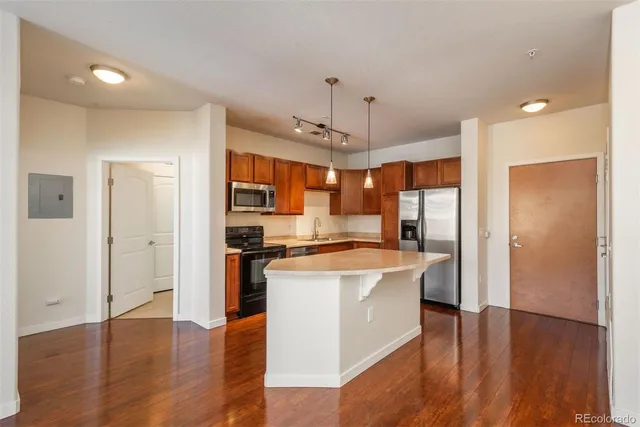 a kitchen with stainless steel appliances granite countertop a refrigerator a stove and a wooden floors