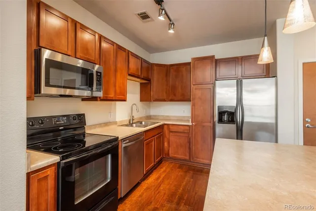 a kitchen with stainless steel appliances granite countertop a stove a sink dishwasher a refrigerator and a microwave oven with wooden floor