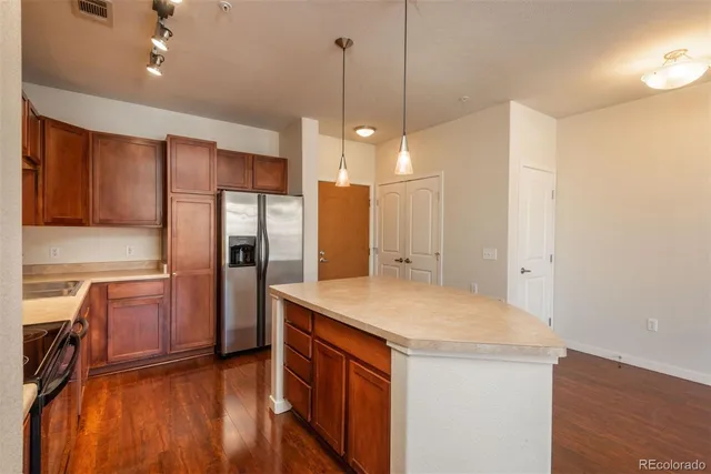 a kitchen with a refrigerator a sink and wooden floor